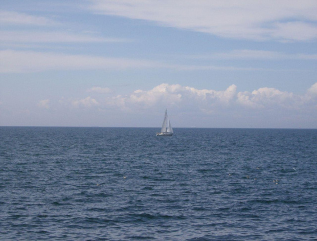 Samotny żagiel na pełnym morzu. Widok ze skał Jons Kapel.